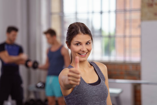 glückliche frau im fitness-studio zeigt daumen hoch