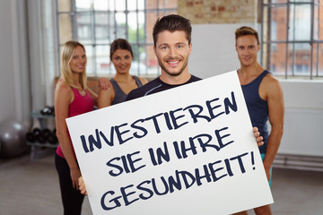 sportler zeigt ein schild mit einem hinweis im fitnessstudio