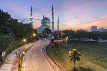 Fototapeta premium View of Shah Alam Mosque with blue skies and white clouds during sunrise.