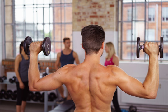sportlicher mann trainiert mit gewichten im fitness-studio