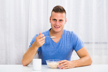 Young man enjoys having a breakfast and drinking coffee at home.
