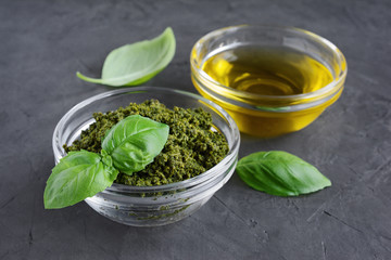 Pesto and olive oil in glass bowl and fresh basil leaves