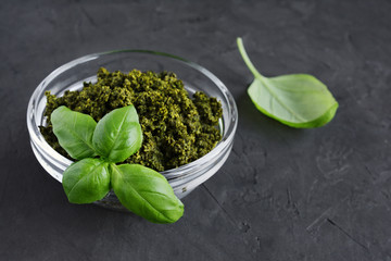 Pesto in glass bowl and fresh basil leaves