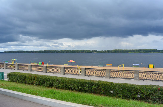 View on the Volga quay of the Samara city in anticipation of thunderstorm. City embankment, green hedgerow, beautiful sky with cumulus clouds before rain at cloudy autumn day