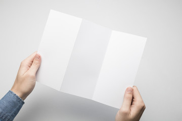 Hands are holding a Dl Z-Fold white paper poster