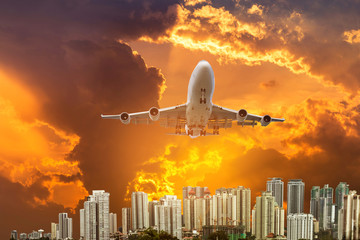 Fototapeta na wymiar airplane flying take off from runway on sunset with modern skyscrapers background
