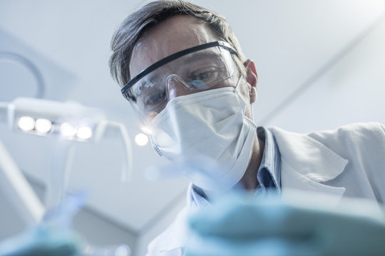 Dentist With Mask And Safety Glasses In Dental Surgery