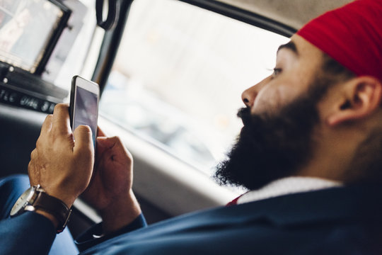 Indian businessman using smartphone in taxi