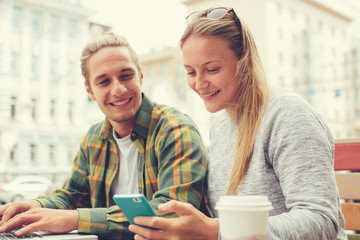 Happy young couple in cafe with laptop and mobile phone