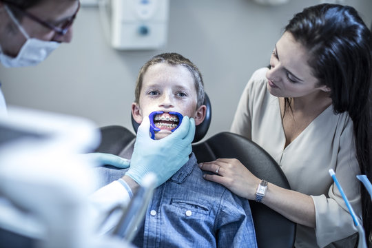 Boy with mother in dental surgery receiving orthodontic treatment