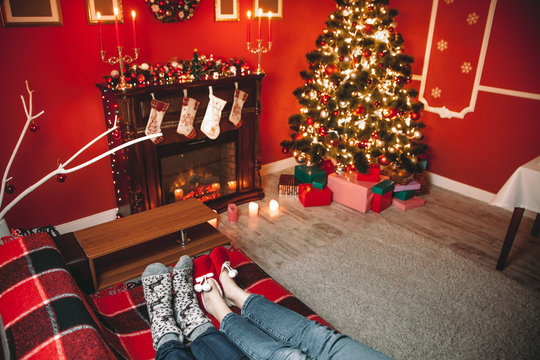 A couple of lovers resting by the fireplace in the Christmas room. Feet in woolen socks warming in winter time.