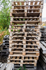 Wooden pallets / wooden pallet overlap in warehouse / stacked wooden pallets / Stacked wooden pallets at a pallet storage /