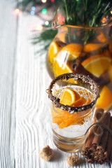 Citrus cocktail in the decorated glass on the white wooden table vertical