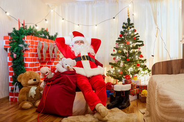 Santa Claus in a chair in the room with the Christmas tree and f