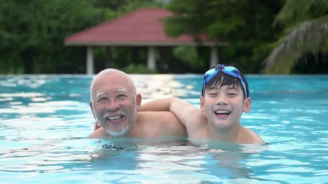 Slow motion of Happy asian family playing in pool, Asian grandchildren and grand parents swimming in pool.