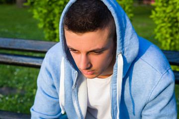 young sad boy in sweater sitting on bench