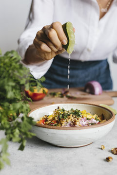 Woman squeezing lime above bowl with walnut salsa