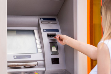 young woman inserting a credit card to ATM