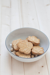 A white bowl with maple leaf shaped cookies 
