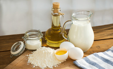 Pancakes ingredients. Milk egg flour oil sugar. Wooden background