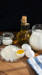 Pancakes ingredients. Milk egg flour oil sugar. Dark background