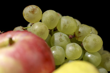 Green grapes behind apples and pears, on black