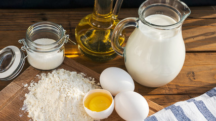 Pancakes ingredients. Milk egg flour oil sugar. Wooden background
