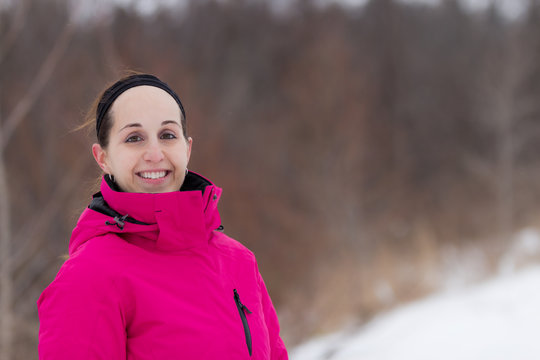 Fit woman in cold weather workout attire near forest during wint