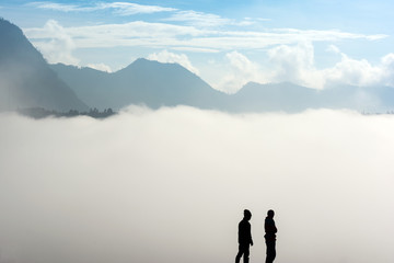 Silhouette of two horsemen resting on the sand dune with foggy / misty morning background at Bromo-Tengger-Semeru National Park, East Java, Indonesia