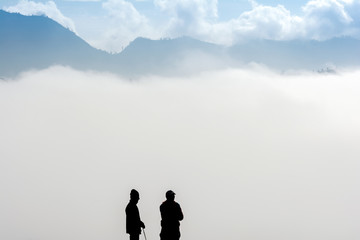 Silhouette of two horsemen resting on the sand dune with foggy / misty morning background at Bromo-Tengger-Semeru National Park, East Java, Indonesia