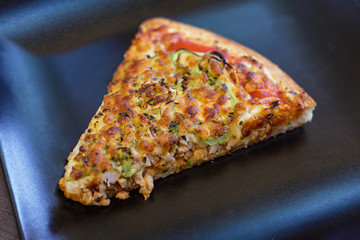 Slice of a Tasty american pizza served on black dish