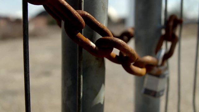 Close up of lock and rusted chain on metal fence
