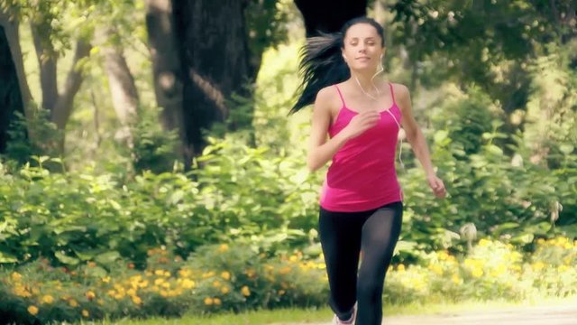 Young woman running in city forest park slow motion HD video. Female jogging: workout fitness outdoor training. Healthy lifestyle sport concept