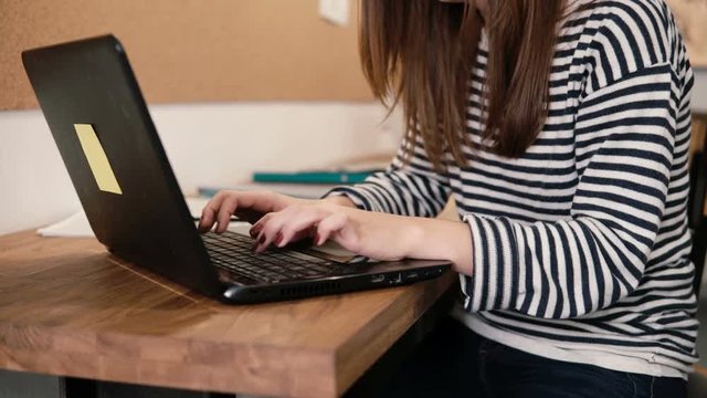 closeup of the hands of young attractive girl uses a laptop in the modern startup office