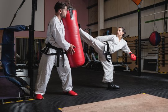 Man and woman practicing karate with punching bag