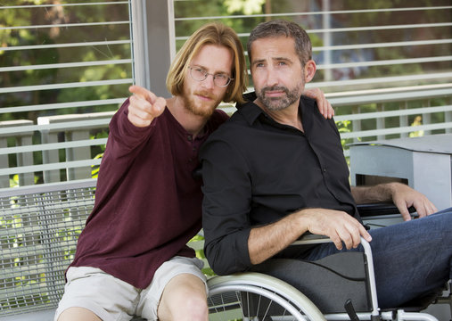 young man showing something to man in wheelchair