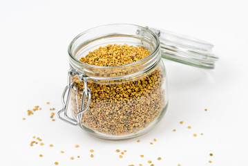 Closeup of bee pollen.Bee pollen granules in glass jar/container. Bee pollen boosts the immune system. Food ingredient, for health, healthy leaving, medical, health-care. Isolated, white background.