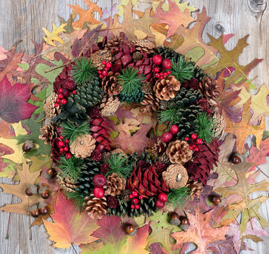 Autumn cone wreath and leaves on rustic wooden boards