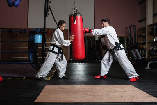 Man and woman practicing karate with punching bag