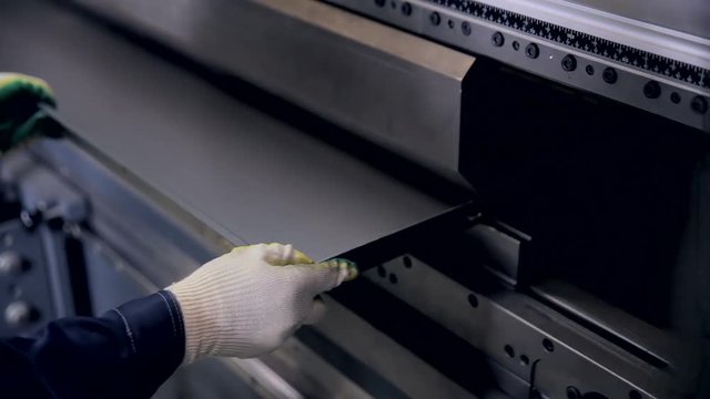 Worker hands bend metal sheet on a modern bending industrial machine at a factory. HD.