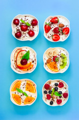 Six yogurts with fresh fruits and berries.