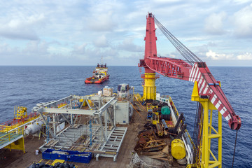 Deck view of construction barge with anchor handling tug in the background