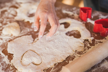 closeup of young caucasian woman making heart-shaped cookies in the kitchen