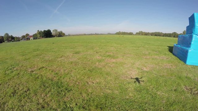 Aerial of white question mark on small bright blue structure drone flying from left to right showing cube with ?  also showing quadcopter shadow and blue sky footage could indicate FAA regulations 4k