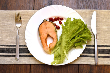 Dish with slice of fried salmon, salad and spicy pepper