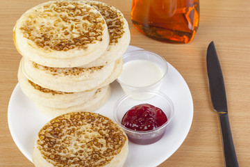 Fresh crumptes on a plate with jam and cream