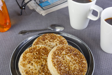 Fresh glazed crumpets and black coffee on the breakfast table