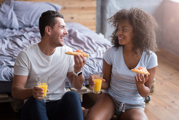 Smiling couple having dinner sitting on the floor