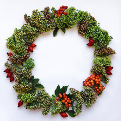 Green floral round wreath frame on white background. Flat lay, top view, view from above. Autumn or winter decoration