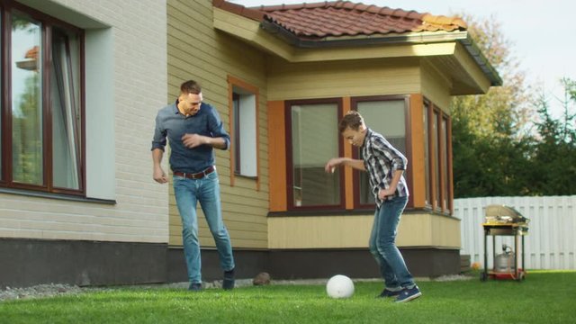 Father and Son Playing With a Ball in the Backyard.